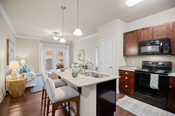 A kitchen with a black stove and wooden cabinets.