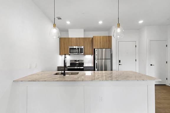 A kitchen with a marble countertop and white cabinets.