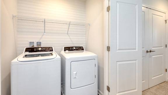 Two white front load washing machines in a laundry room.
