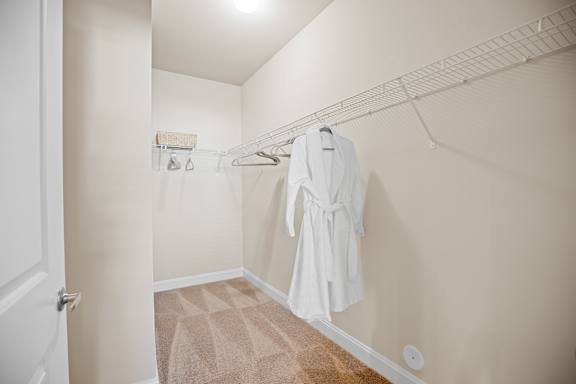 A white robe is hanging on a rack in a small, empty room.