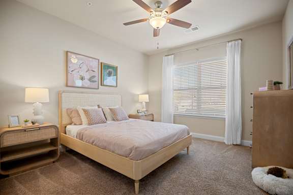 A bedroom with a bed, nightstand, and a ceiling fan.