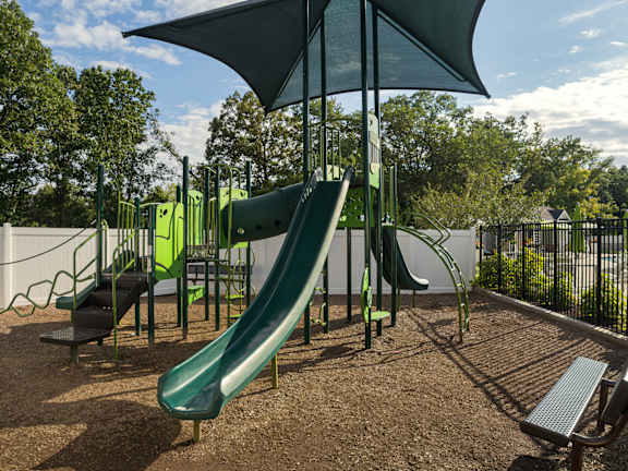 A playground with a green slide and a bench.