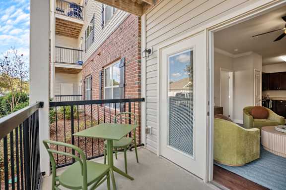 A balcony with a table and chairs overlooks a brick building.