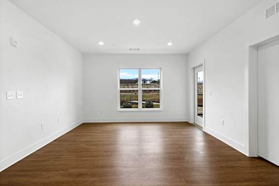 A large empty room with a window and wooden floors.