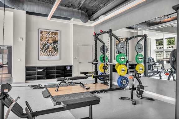 A gym with a variety of equipment including weights and a bench.