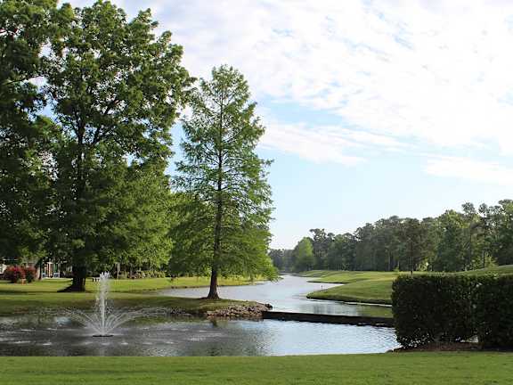 A fountain in the middle of a lake surrounded by trees.