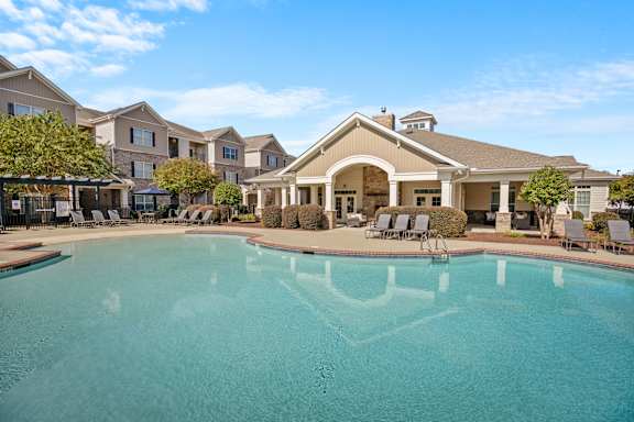 A large swimming pool in front of a building with a covered patio area.