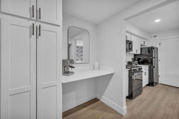 A kitchen with white cabinets and a wooden floor.
