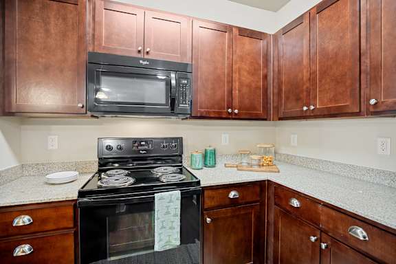 A black stove and microwave in a kitchen with brown cabinets.