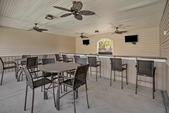A patio with a table and chairs and a ceiling fan.