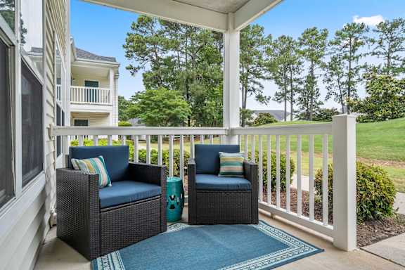 Two chairs and a table on a porch.