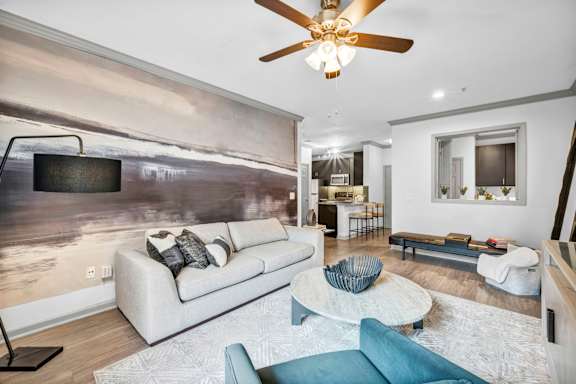 A modern living room with a large painting on the wall and a ceiling fan.