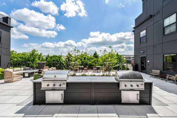 A grill is on a patio with a building in the background.