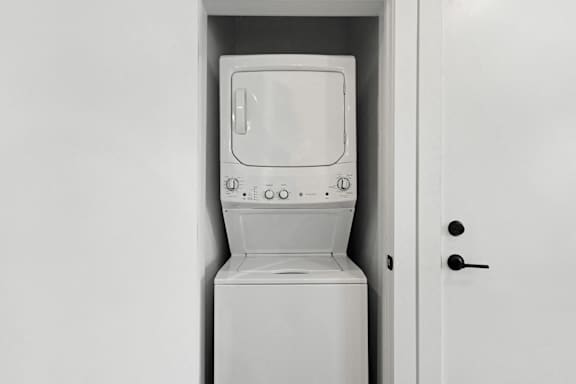 A white washing machine is sitting in a white door.