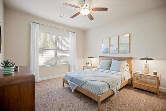 A bedroom with a bed, nightstand, and a ceiling fan.