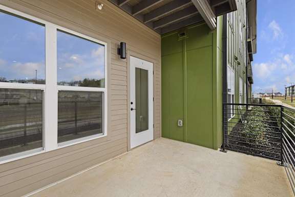 A balcony with a green door and a black railing.