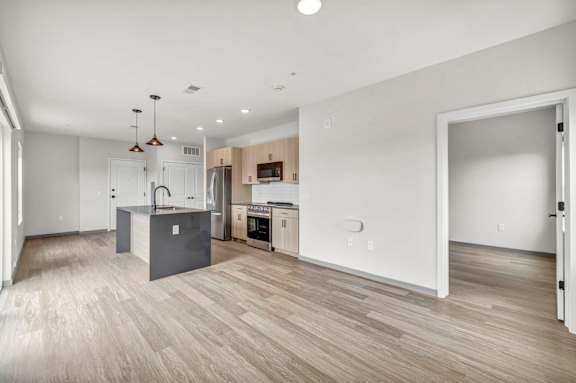 A spacious kitchen and living room with wooden flooring and modern appliances.