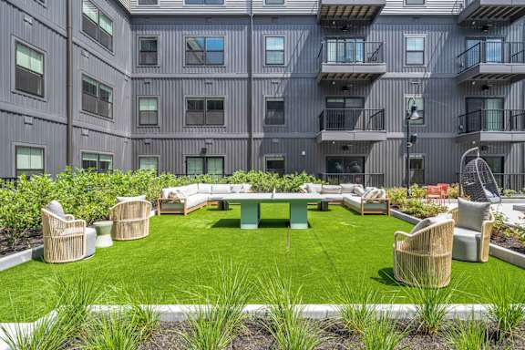 A large grassy area with chairs and tables in front of a building.