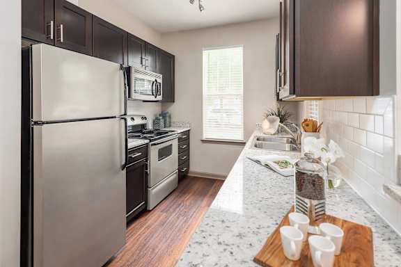 A kitchen with a refrigerator, oven, and microwave.
