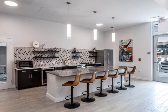 a large kitchen with a long counter and chairs at Centro at Pine Nash in Wilson, NC 27893