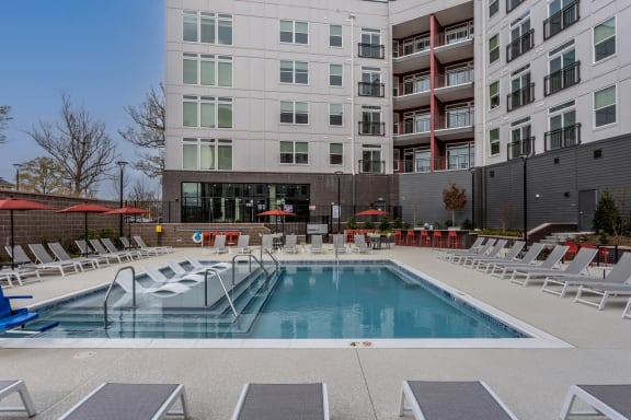 a swimming pool at a building with chairs around it at Centro at Pine Nash in NC 27893