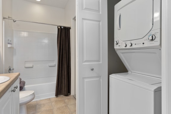 a white washer and dryer in a bathroom with a shower and a toilet at The Charleston, Columbus, OH