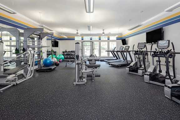 A spacious gym with various exercise equipment and a blue exercise ball.