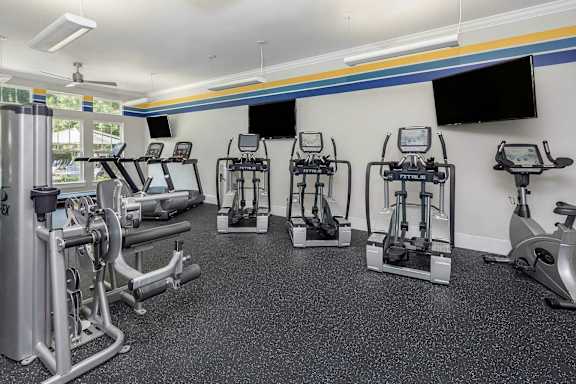 A gym with a variety of equipment including treadmills, stationary bikes, and weight machines.