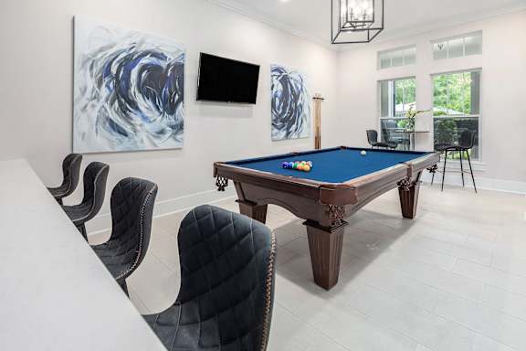 A pool table is surrounded by chairs in a room.