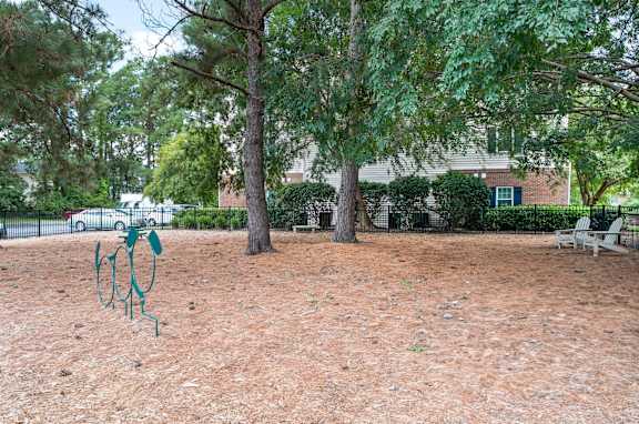 A playground with a swing set in the middle of a dirt area at Litchfield Oaks Apartments in Pawleys Island, SC