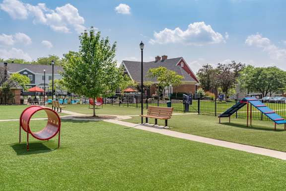 A playground with a red slide, a blue slide, and a brown bench.