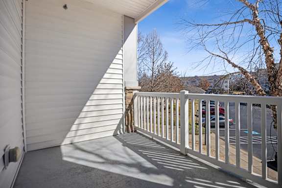 A white balcony with a metal railing and a white wall.