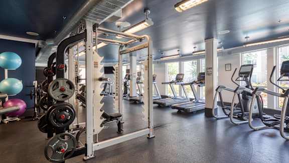 A gym with a variety of equipment including treadmills, weights, and exercise machines.