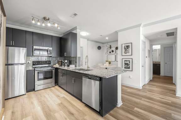 A modern kitchen with a refrigerator, oven, and sink.