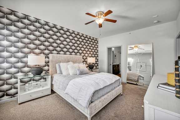 A bedroom with a bed, dresser, and a ceiling fan.