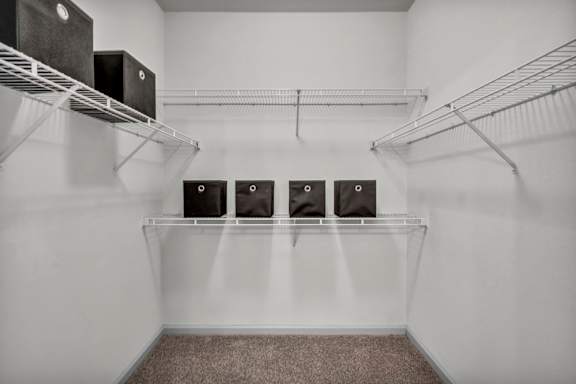 A room with a white wall and a shelf with four speakers on it.