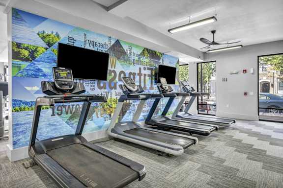 A gym with treadmills and a wall mural.
