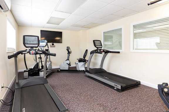 A room with a treadmill, elliptical trainer and a stationary bike.