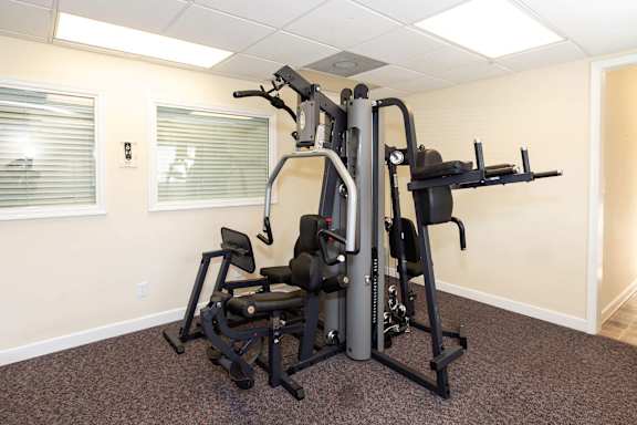 A gym room with a multi-station workout machine.