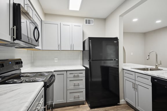 an empty kitchen with white cabinets and black appliances at Shellbrook, Raleigh, NC