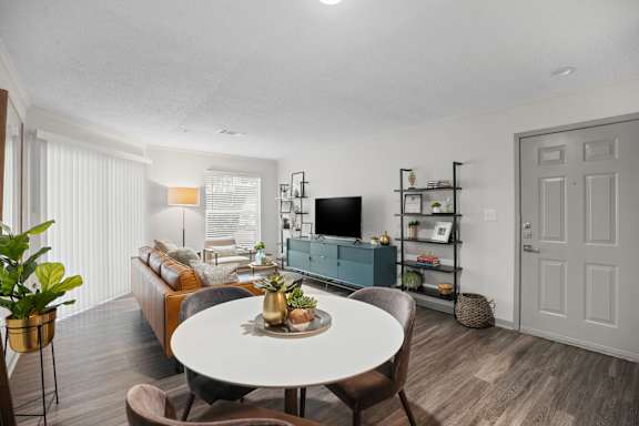 A living room with a white table and brown chairs.