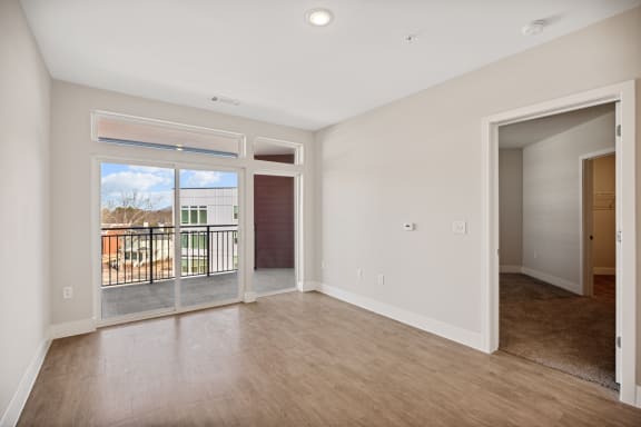an empty living room with sliding glass doors to a balcony at Centro at Pine Nash in Wilson, NC