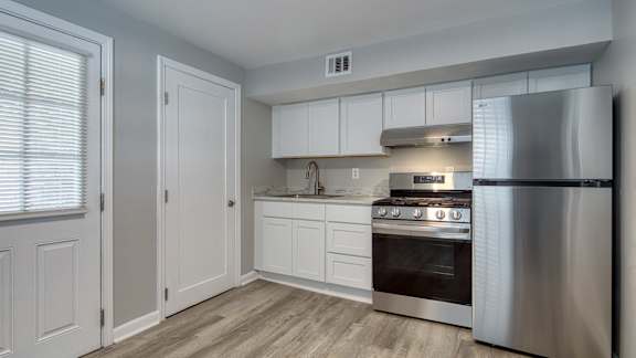 A modern kitchen with a stainless steel refrigerator, oven, and cabinets.