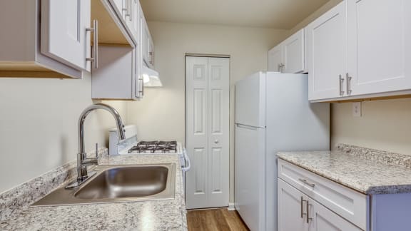 a kitchen with white cabinets and a sink and a refrigerator at Gates of West Bay in Norfolk, Virginia