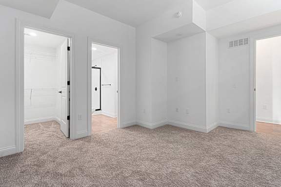 A white room with a carpeted floor and a doorway leading to another room.