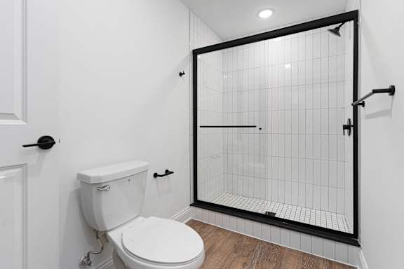 A white toilet in a bathroom with a black shower door.