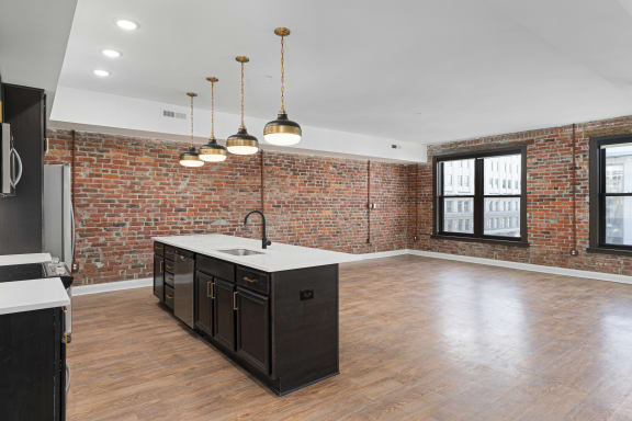 the kitchen has a large island with a sink and a brick wall at The Madison in Columbus, Ohio