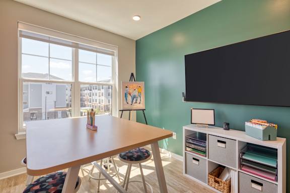 A room with a table, chairs, and a large window overlooking a cityscape.