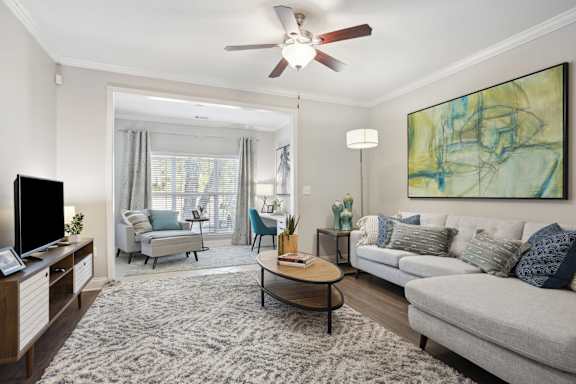 A living room with a grey couch, a coffee table, a television, and a painting on the wall.