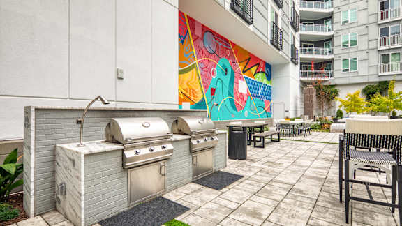 A patio with a grill and a colorful mural on the wall at Mosaic Summit Pointe in Chesapeake, VA, 23320
